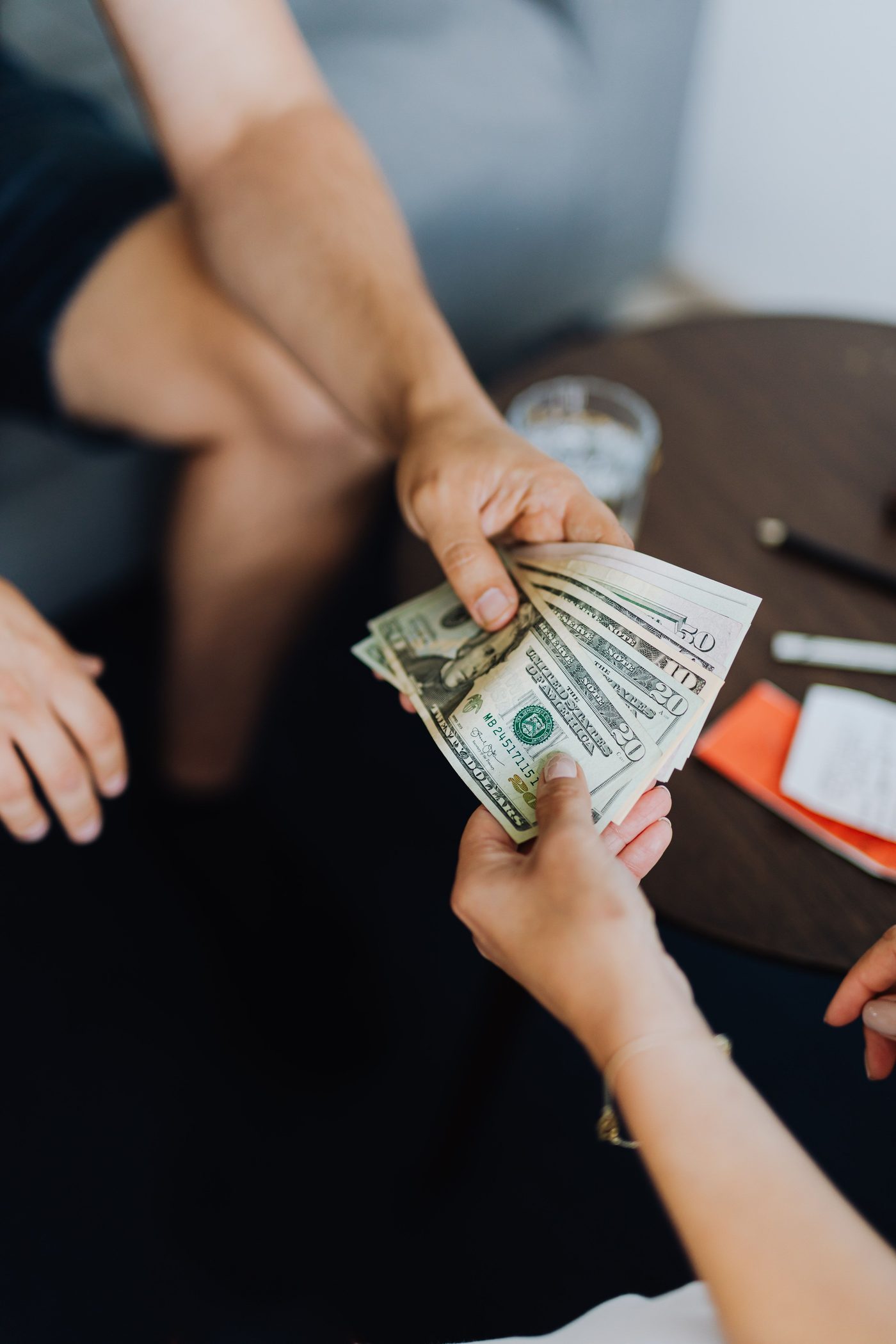 Close-up of one person handing a fanned stack of cash to another person, representing an installment loan payout